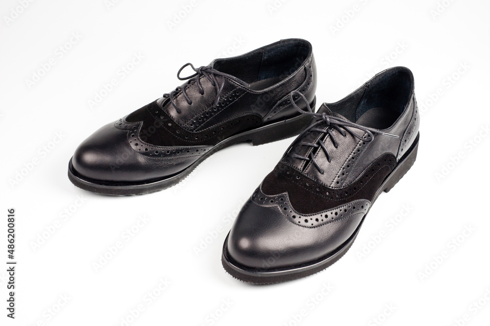 Black imitation leather shoes laced with wide laces. Close-up shot.