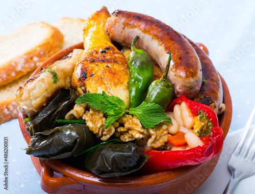 National festive Bulgarian dish Kapama - stew from several types of meat and sausages with stuffed vegetables served with greens and walnuts.. photo