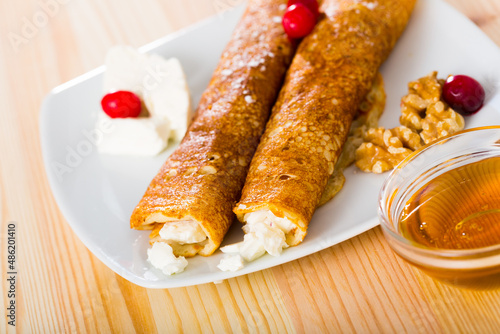 Bulgarian-style crepes Palatschinke with filling of brinsen cheese and walnuts with honey on white dish photo