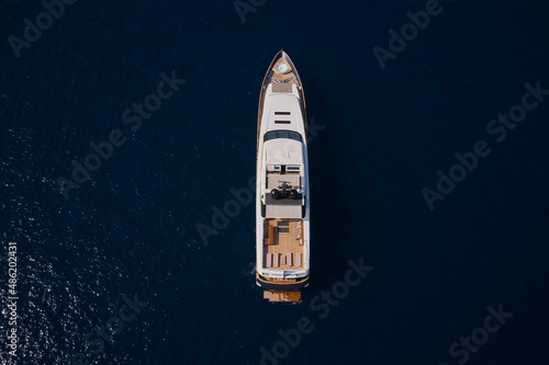 Big yacht for millionaires in the sea drone view. Luxurious white mega yacht on dark water in the reflection of the sun top view.