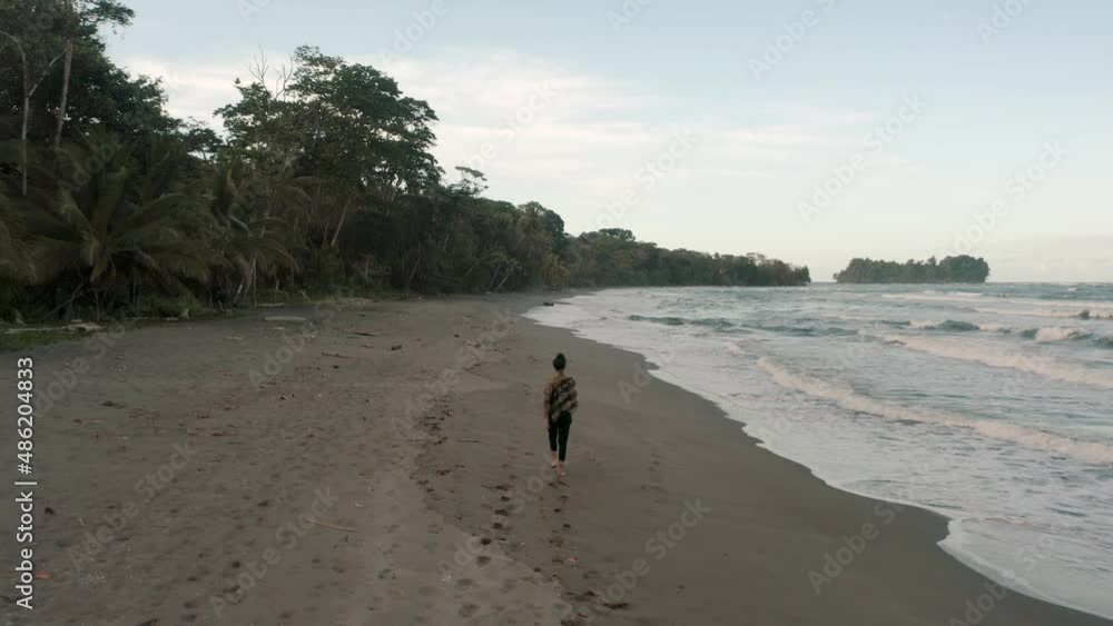 Female Tourist Walking On The Tropical Beach Of Punta Mona In Costa Rica - aerial drone shot Female Tourist Walking On The Tropical Beach Of Punta Mona In Costa Rica - aerial drone shot