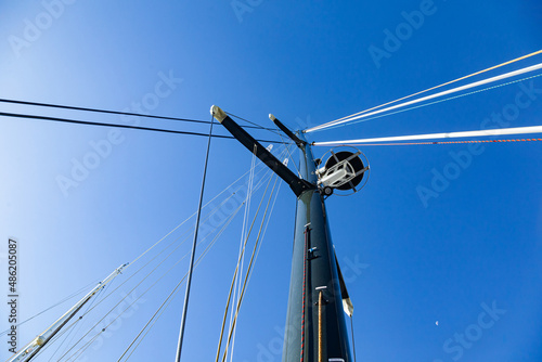 The mast of a sailing yacht with a radar, sail ropes and a folded sail, viewed from below against the sky. photo