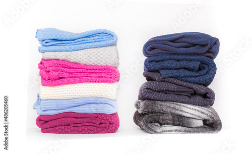Knitted winter clothes neatly folded in a pile on a white background. The surface of men's woolen things, textiles. Closeup knitted texture. Background with copy space. Casual wear.