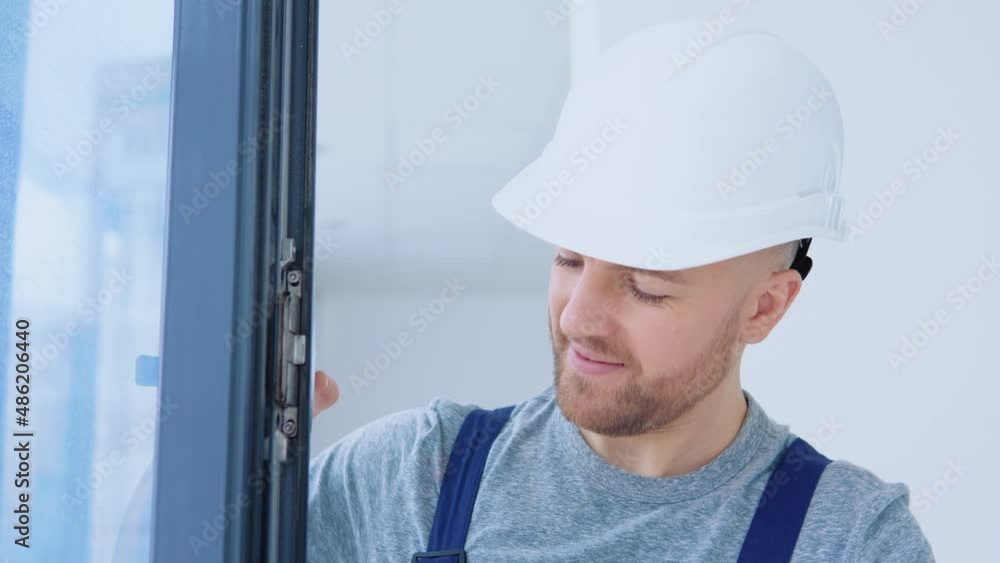 Window installer in a helmet and a screwdriver installs windows Window installer in a helmet and a screwdriver installs windows