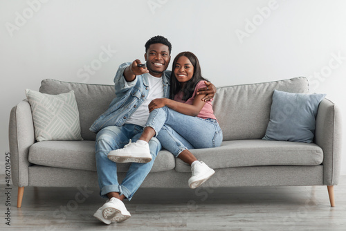 Happy black couple spending weekend together watching tv