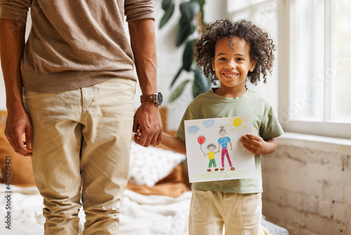 Cute little african american boy son holding hand drawing with happy family for dad on Fathers day