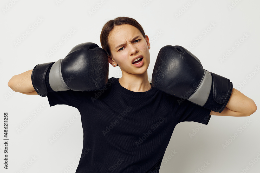 young beautiful woman in black sports uniform boxing gloves posing isolated background
