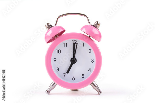 Mechanical classic pink alarm clock (hands at 7 o'clock in the morning) on a white isolated background.