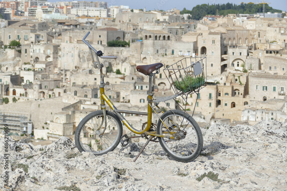 vintage folding bicycle on the edge of the precipice with the old town of Matera in the background