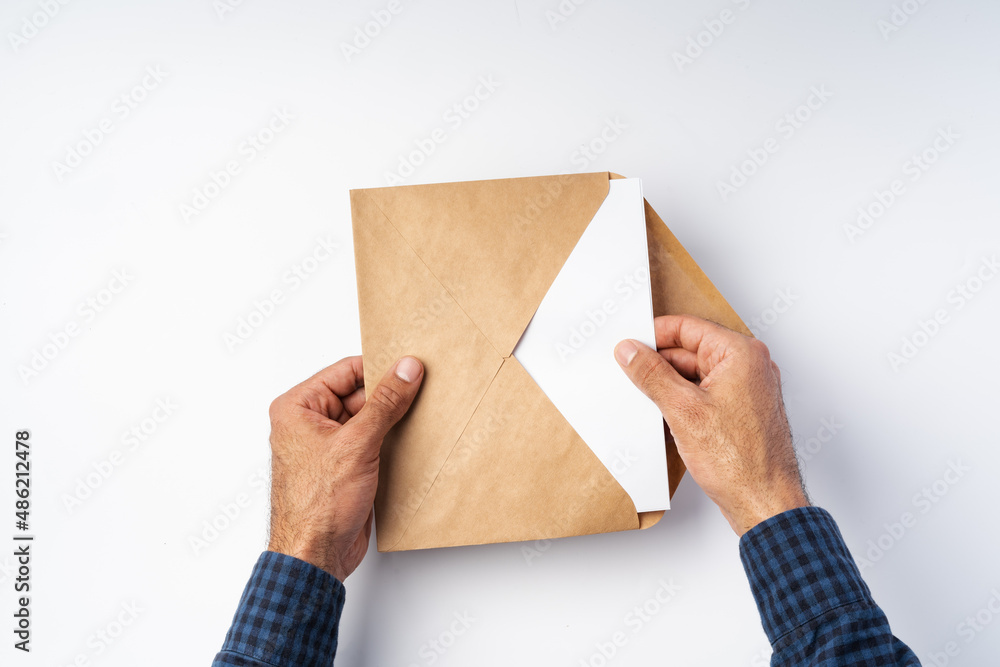 Top view of male hands hold (open) an envelope above white background