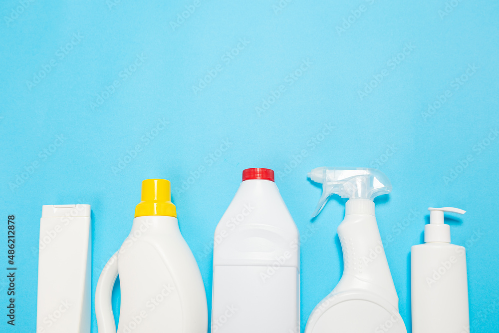 House cleaning supplies on blue background. Row of plastic bottles with cleaning liquid and sponges. Cleaning business, production, shopping and delivery. copy space on top. House cleaning supplies on blue background. Row of plastic bottles with cleaning liquid and sponges. Cleaning business, production, shopping and delivery. copy space on top.