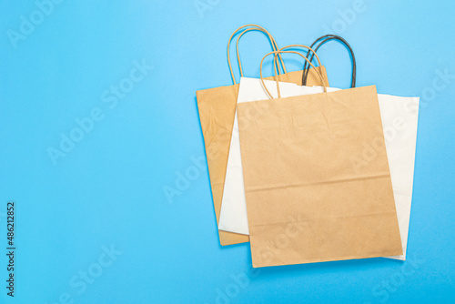 Blank brown paper carrier bag with handles for shopping, facing front on blue background Commercial, sale and advertisement concept.