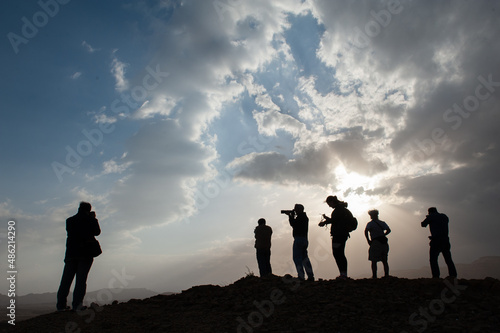 Silhouette of a group of photographers during a workshop at sunset on a desert hilltop. 