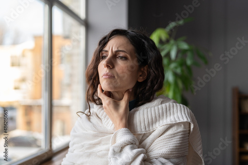 Photo Upset sick woman standing at home touching swollen glands, having pain or scratchy sensation in throat, selective focus