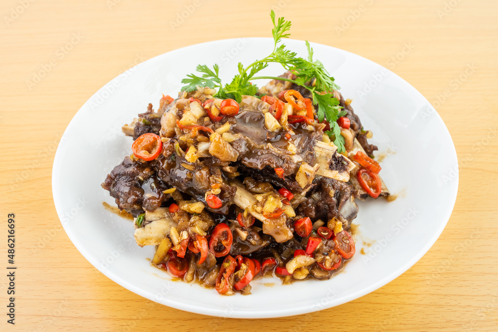 A plate of spicy beef ribs on a wooden table A plate of spicy beef ribs on a wooden table