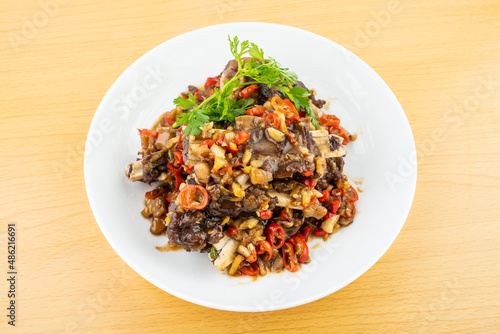 A plate of spicy beef ribs on a wooden table