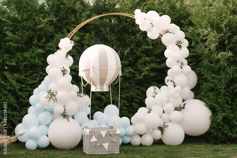 Decorations for holiday party. A lot of balloons blue and white colors. Round photo zone with balls next to a ball with a basket for a child