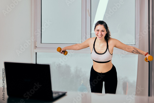 Live streaming classes of fitness on laptop for smiling woman in sportswear.