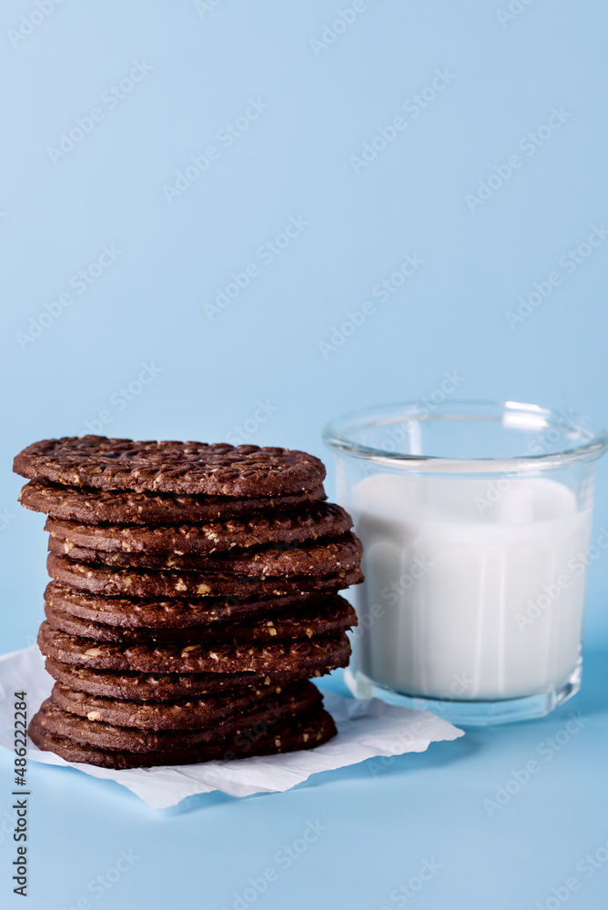 Glass of Milk and Oatmeal Chocolate Cookies on a Blue Background Vertical Glass of Milk and Oatmeal Chocolate Cookies on a Blue Background Vertical