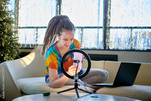 Female vlogger uses ring light and handy for live stream.