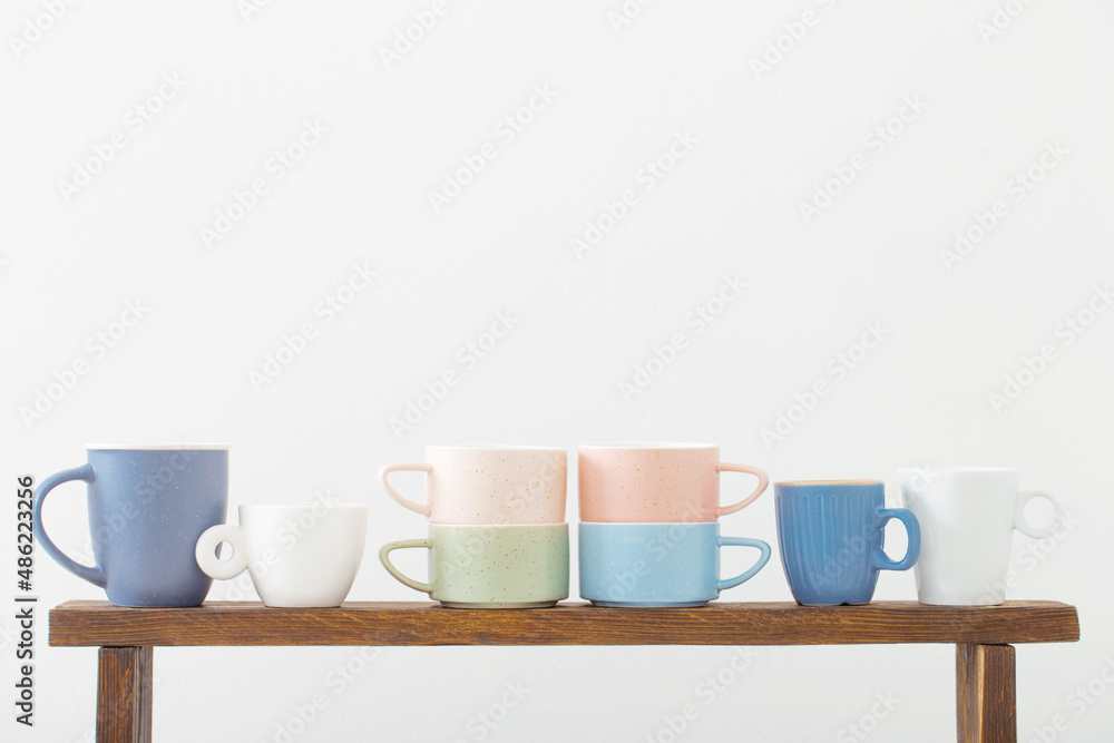 colorful cups on wooden shelf on white background colorful cups on wooden shelf on white background