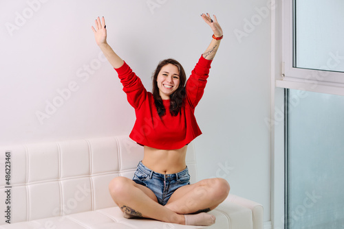 Panoramic window with happy young woman on sofa near.