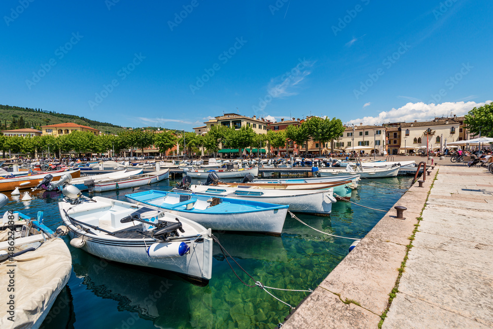 Small port of Lake Garda (Lago di Garda) with many boats moored, and cityscape of Garda, famous tourist resort in Verona province, Veneto, Italy, southern Europe.