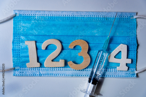 Fourth covid vaccine dose and jab concept with face mask. Syringe is seen on table as a concept for the 4th covid-19 vaccine dose, also called booster shot to fight the spread of covid omicron variant photo