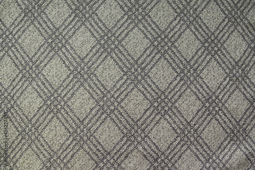The texture of gray plaid suit fabric is close-up with diagonal threads for a traditional business background in neutral tones. Checkered pattern, diagonal fabric background, grunge material.