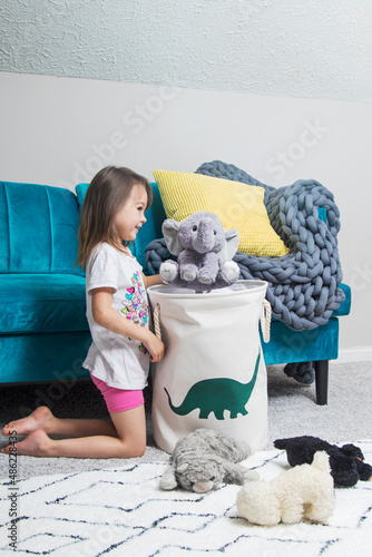Young girl puts toys away in cloth basket