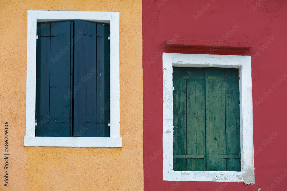 Fototapeta premium Old walls of red and orange with the windows closed shutters, Burano, Venice