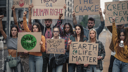 Crowd of activists protesting against climate policy and global warming with raised fists and slogans on placards - concept that illustrates the sensitivity of generation z towards social problems photo