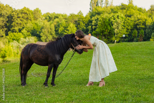 woman petting a pony standing on the lawn