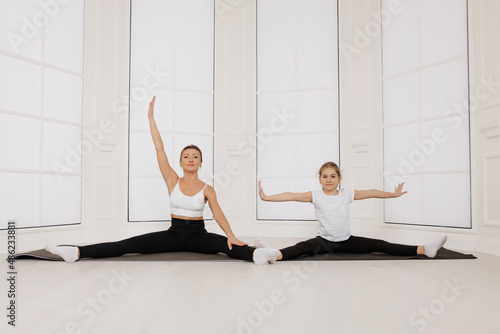 Fototapeta Naklejka Na Ścianę i Meble -  Young stylish mother trainer together with little daughter doing pilates sport gymnastic exercise