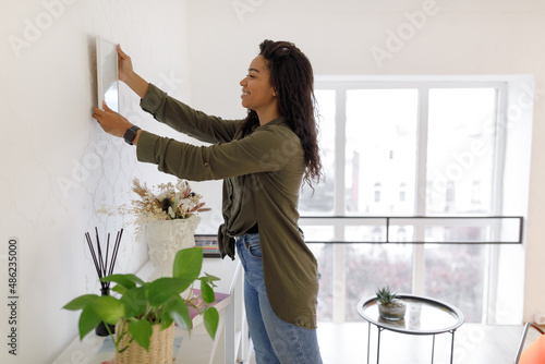 Black woman hanging picture frame on the wall photo