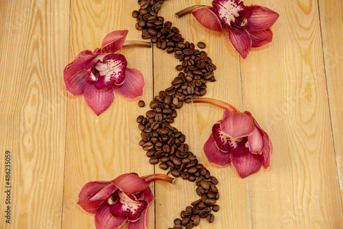 Scattered coffee beans, espresso. orchid flowers are laid out. The concept of coffee. brazilian coffee. on a wooden background. still-life