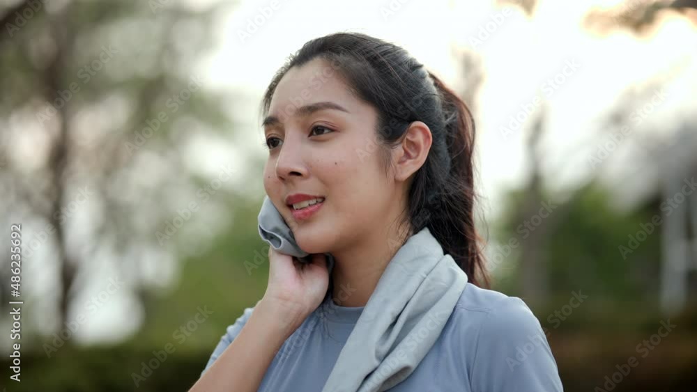 Slim beautiful woman wiping sweat on face and neck during exercise in the city at sunrise. Young asian female take a break from training before workout, cardio. Healthy and active lifestyle concept. Slim beautiful woman wiping sweat on face and neck during exercise in the city at sunrise. Young asian female take a break from training before workout, cardio. Healthy and active lifestyle concept.