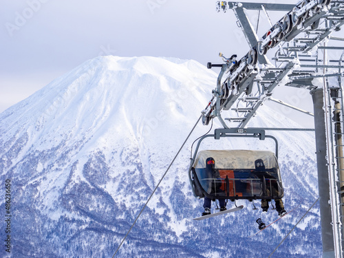 Chairlift with a snowy volcano in background (Niseko, Hokkaido, Japan) photo