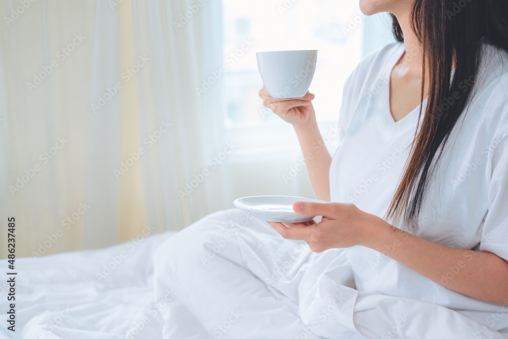 Asian woman drinking coffee in the morning in bed. Asian woman drinking coffee in the morning in bed.
