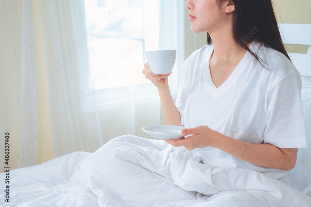Asian woman drinking coffee in the morning in bed. Asian woman drinking coffee in the morning in bed.