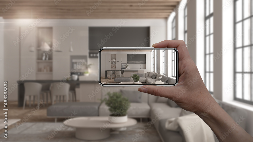 Hand holding smart phone, AR application, simulate furniture and interior design products in real home, architect designer concept, blur background, modern living room and kitchen Hand holding smart phone, AR application, simulate furniture and interior design products in real home, architect designer concept, blur background, modern living room and kitchen