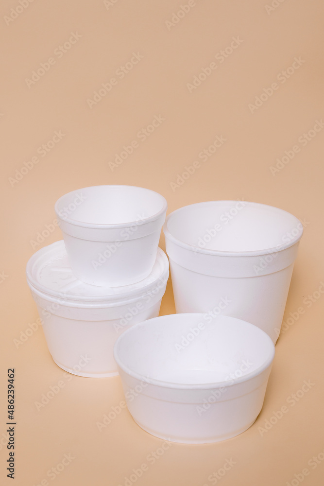 Disposable plastic containers for food on a peach background. Concept of using eco utensils. Disposable plastic containers for food on a peach background. Concept of using eco utensils.
