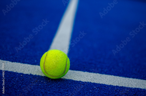 selective focus of a ball on the white line of a blue paddle tennis court © Vic