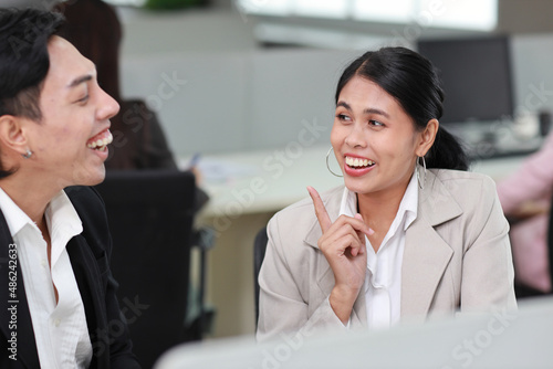 Business people gossiper group whispering or sharing rumor about their colleague in the office. Female coworker sitting and telling gossip to male workmate about bullying problem at work place photo