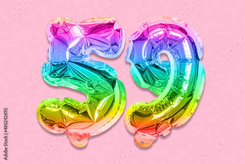Rainbow foil balloon number, digit fifty nine on a pink background. Birthday greeting card with inscription 59. Top view. Numerical digit. Celebration event, template. photo
