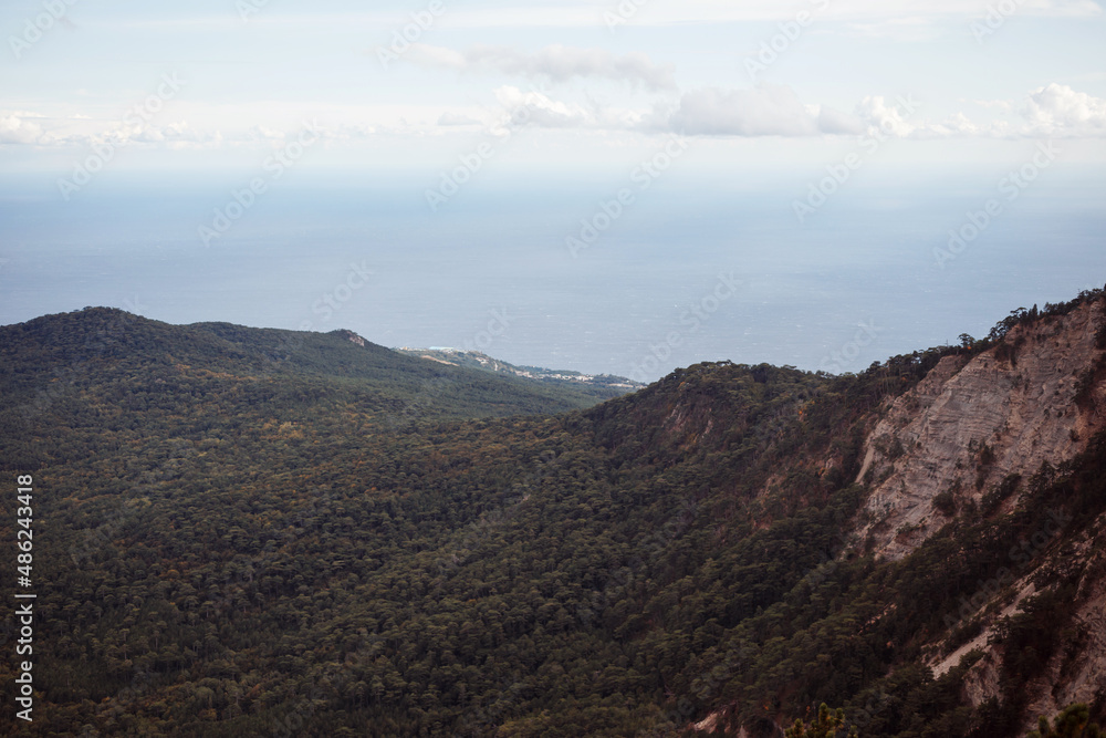Forested mountains, sky and sea landscape.