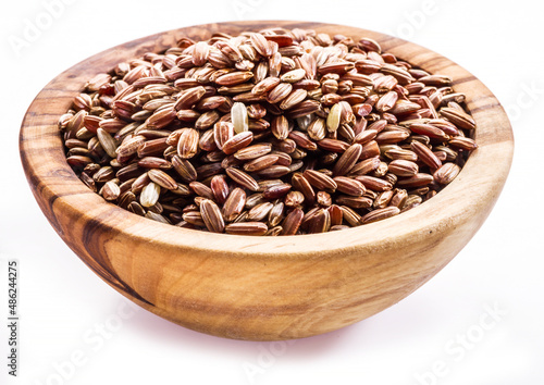 Brown rice - whole grain rice with outer hull or husk in wooden bowl on white background.