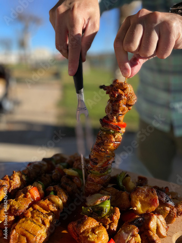 Close-up of some hands preparing meat skewers prepared on a barbecue