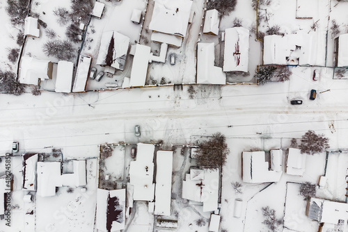 Top-down view of street with houses in snow-covered village on winter day after snowfall