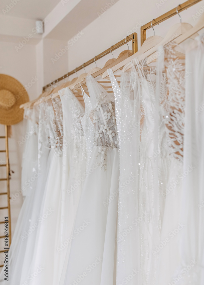 Wedding dresses hanging at a bridal showroom. New collection of bohemian style wedding gowns.